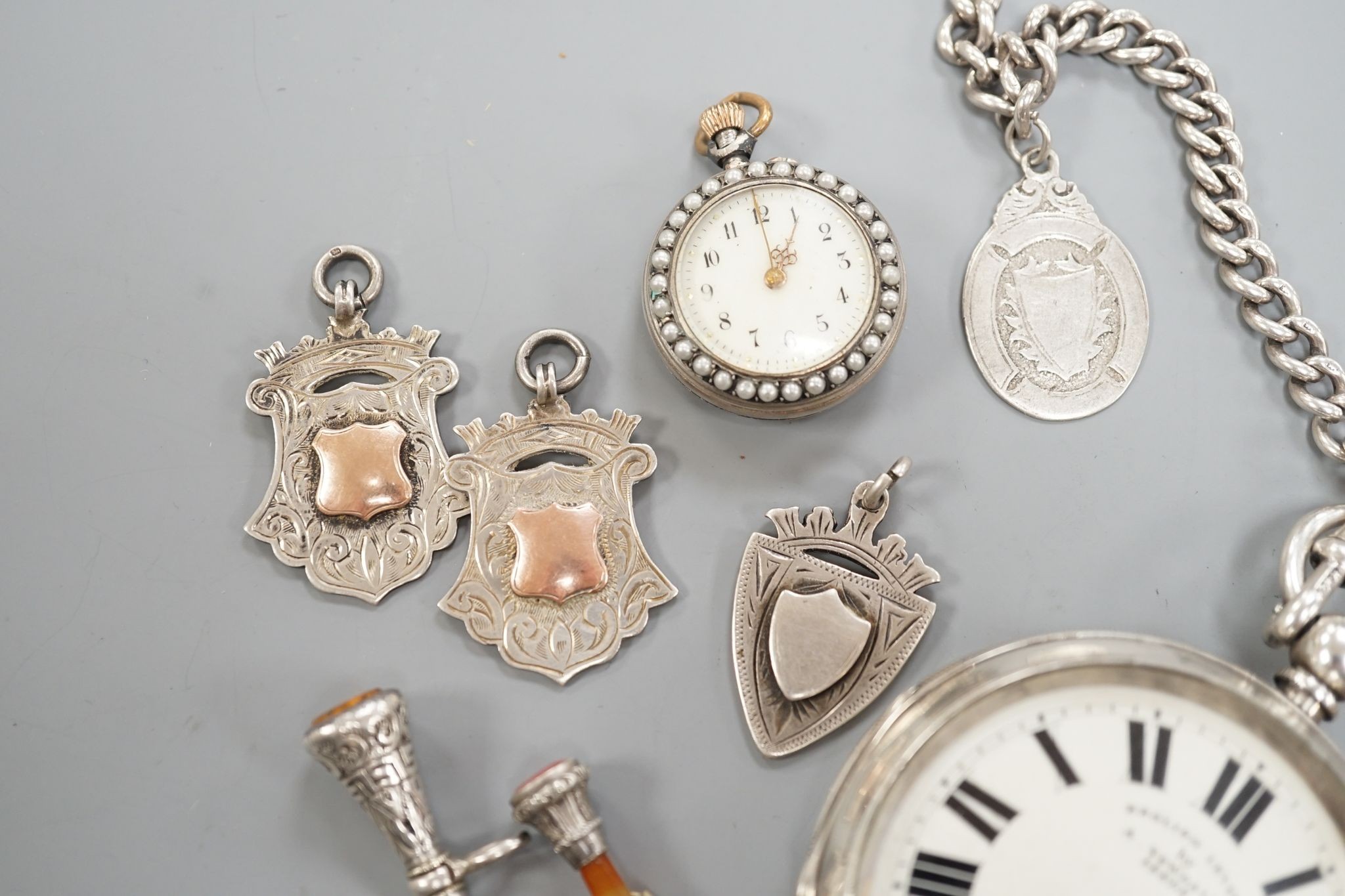 A George V silver open faced lever pocket watch, by A. Yewdall, Leeds, on a silver albert hung with silver medallions, two Swiss white metal and enamel fob watches, gilt fob seal, etc.